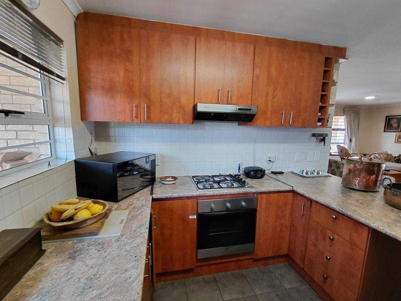 A functional kitchen featuring wooden cabinetry, laminate countertops, a built-in oven, gas hob, and a tiled backsplash.
