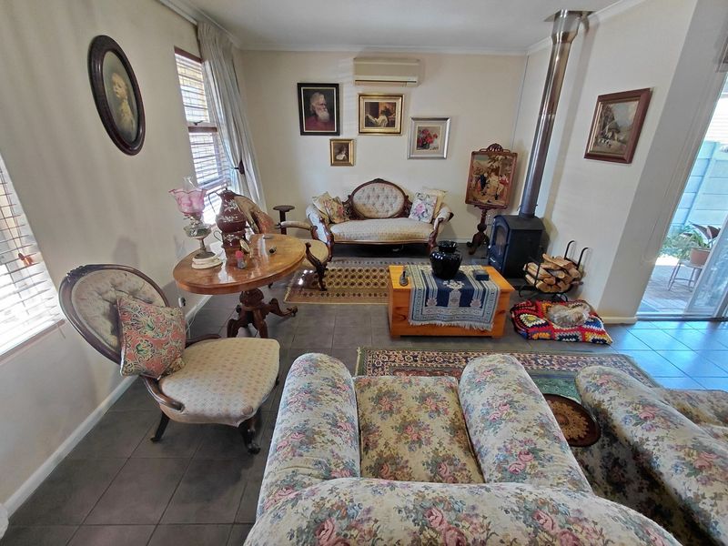A cozy living room featuring tiled flooring, a wood-burning stove, and a split-system air conditioner, with direct access to an outdoor area.