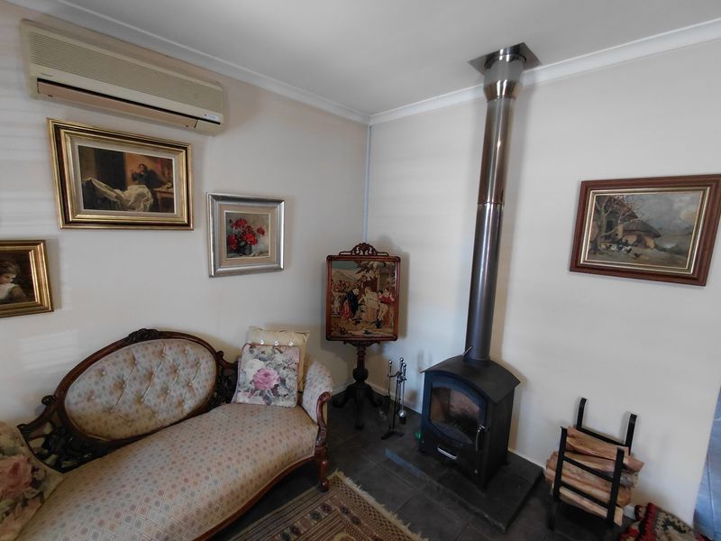 A cozy living area featuring a wood-burning stove with a stainless steel flue, tiled flooring, and a wall-mounted split-system air conditioner.