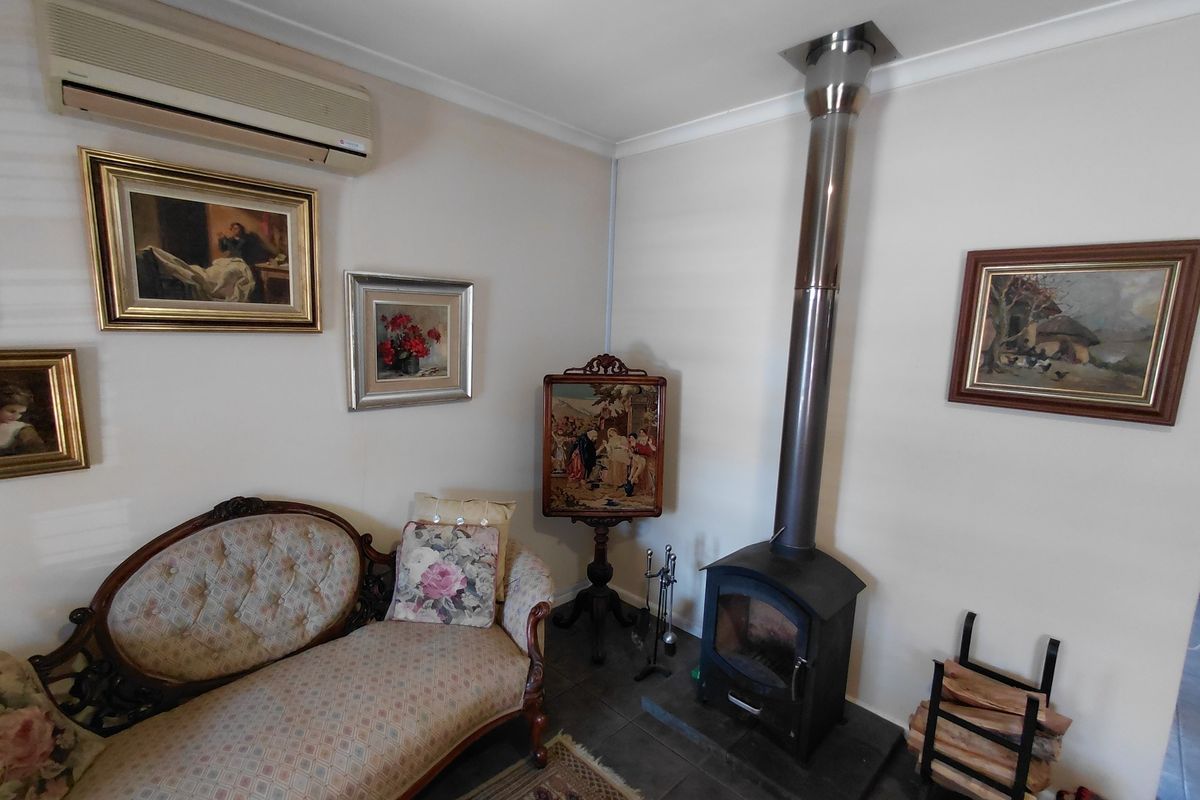 A cozy living area featuring a wood-burning stove with a stainless steel flue, tiled flooring, and a wall-mounted split-system air conditioner.