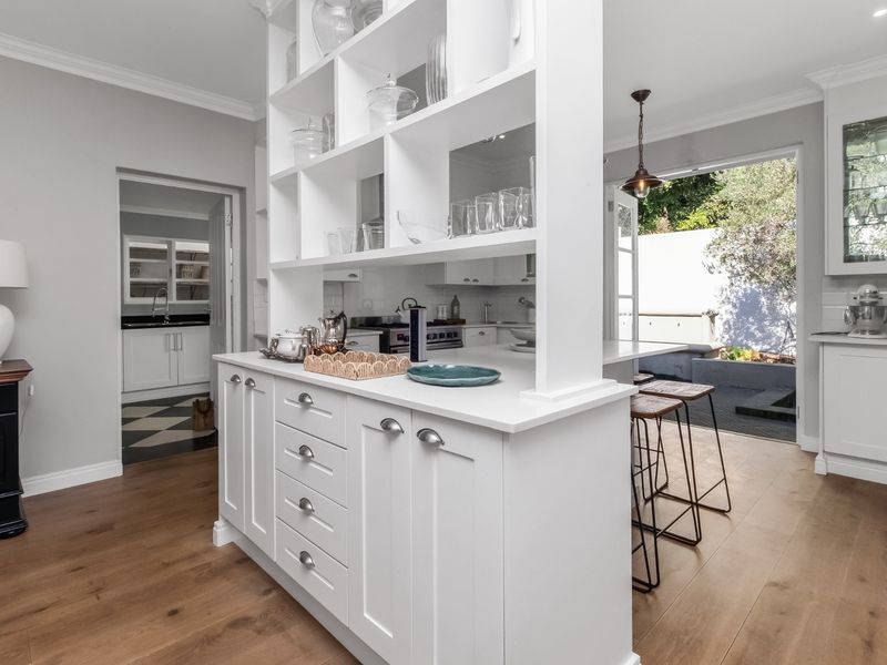 Modern kitchen featuring a central island with integrated shelving, hardwood flooring, and seamless flow to the outdoor patio area.