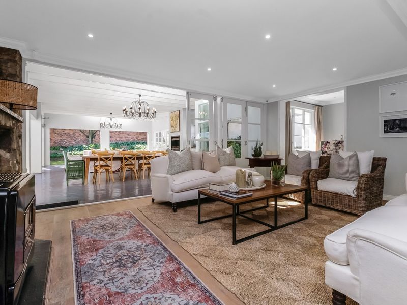 Spacious open-plan living area featuring a stone fireplace with wood-burning stove, timber flooring, and seamless flow to a covered outdoor patio.