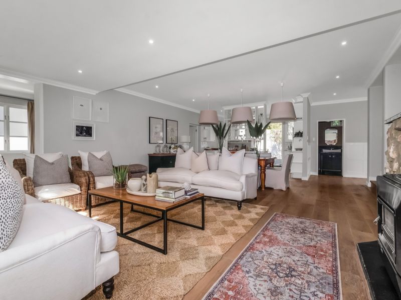 Spacious open-plan living area featuring hardwood floors, recessed lighting, and a prominent stone fireplace with a wood-burning stove.