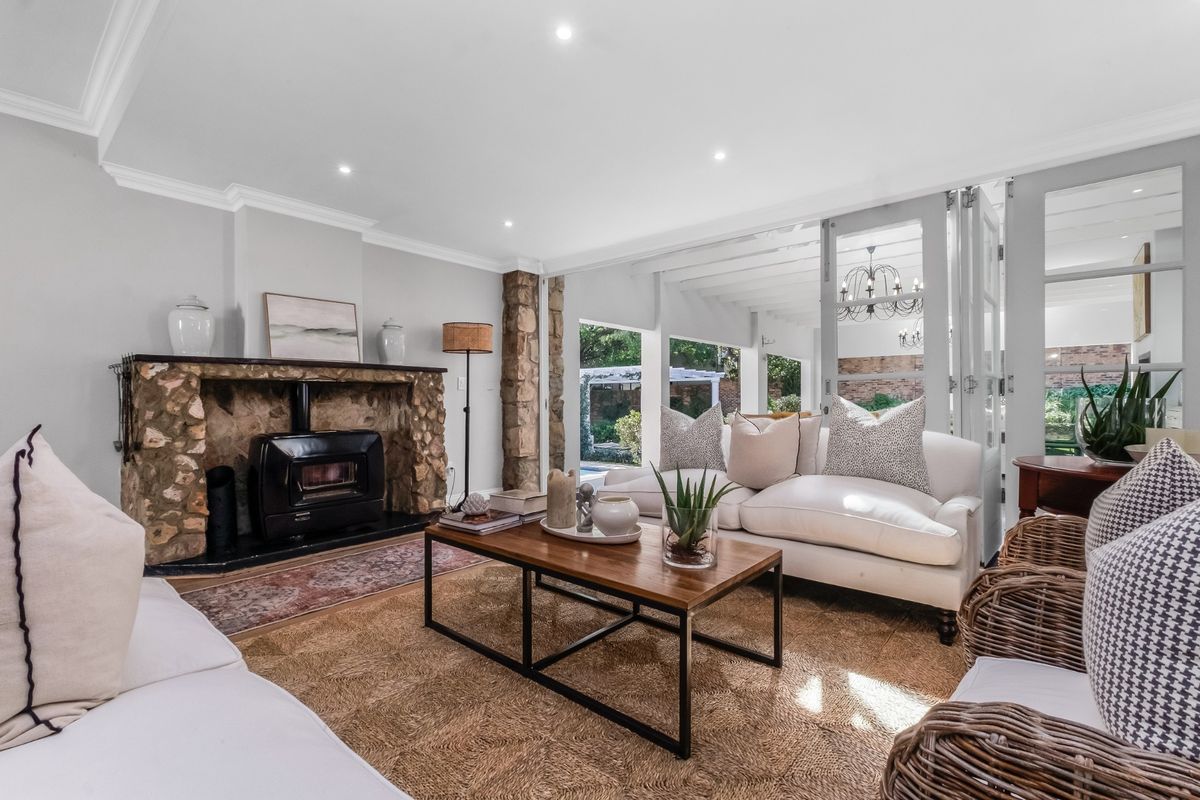 Inviting living room featuring a rustic stone fireplace with a wood-burning stove, recessed lighting, and bi-fold doors opening to the outdoor area.