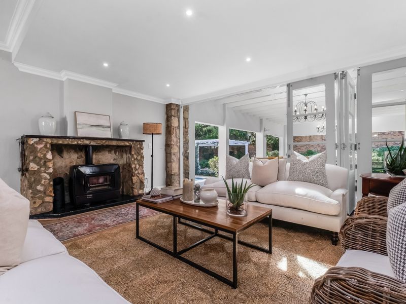 Inviting living room featuring a rustic stone fireplace with a wood-burning stove, recessed lighting, and bi-fold doors opening to the outdoor area.