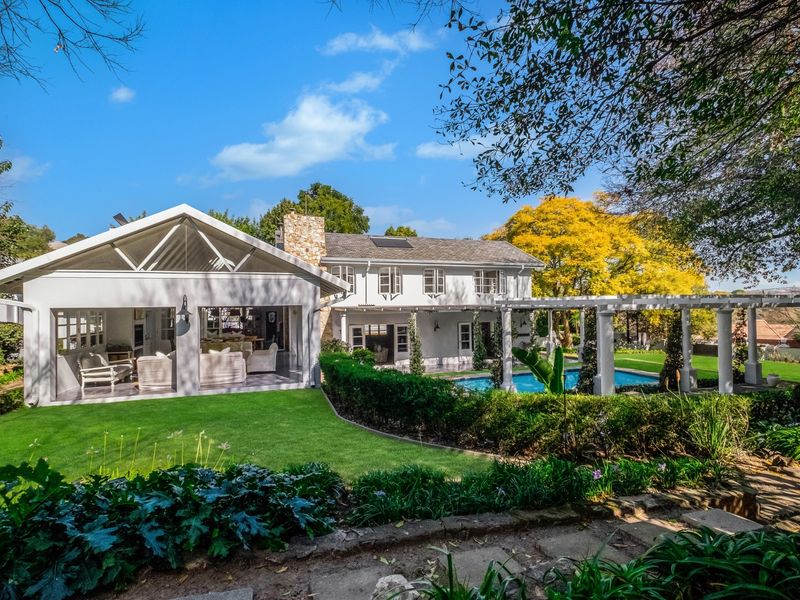 Spacious rear exterior featuring a swimming pool, a large covered patio area, a pergola, and a well-maintained landscaped garden.