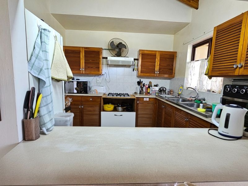 A functional kitchen featuring wooden cabinetry, a gas hob, built-in oven, and a double sink with a tiled backsplash.