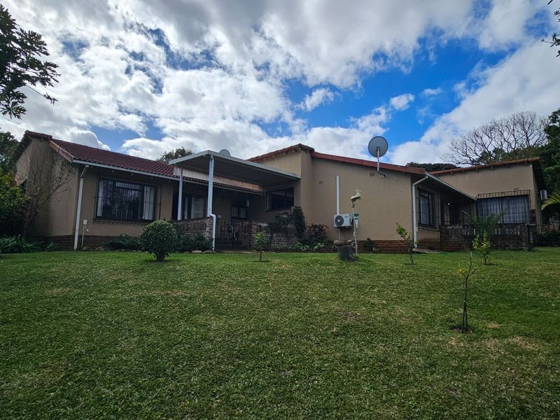 Rear view of the townhouse featuring a covered patio, tiled roof, and established garden area.