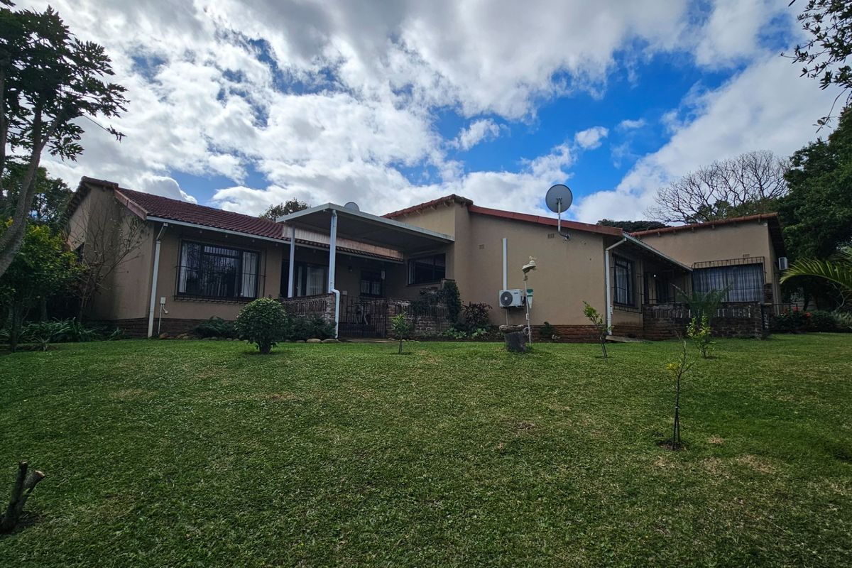 Rear view of the townhouse featuring a covered patio, tiled roof, and established garden area.