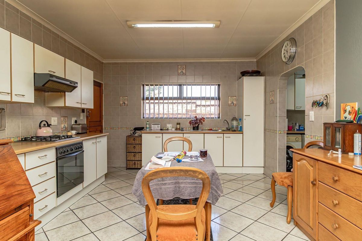 A functional kitchen featuring tiled flooring, wall-to-wall tiling, built-in cabinetry, a gas hob, and an integrated oven with an extractor fan.