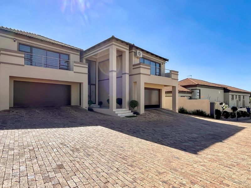 Modern double-story residential property featuring a paved driveway, double garage, and upper-level balconies with a clean, well-maintained facade.