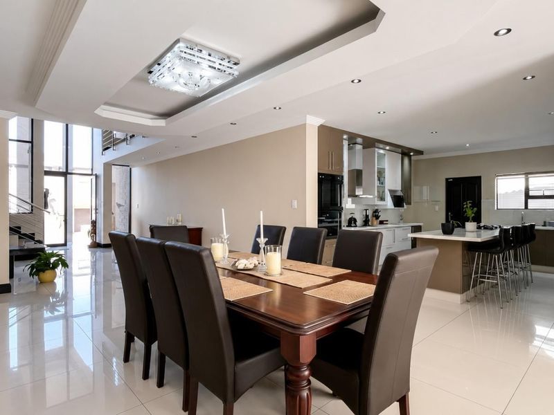 Spacious open-plan living and dining area featuring high-gloss floor tiles, a modern kitchen with a central island, and elegant recessed ceiling lighting.