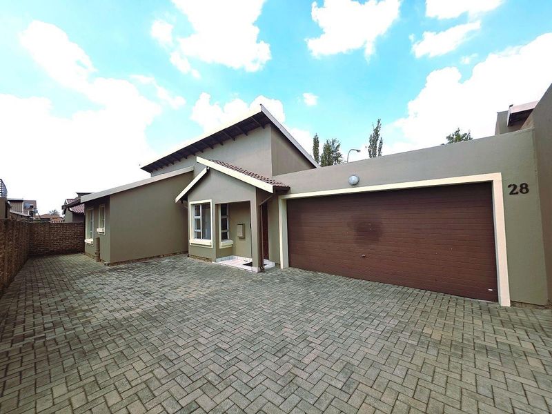 Front view of a townhouse featuring a paved driveway, double garage, and well-maintained exterior facade.