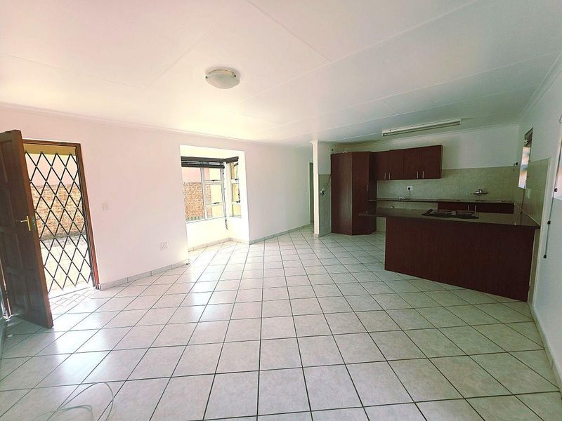Spacious open-plan living area featuring tiled floors and a functional kitchen with built-in cabinetry and a breakfast island.