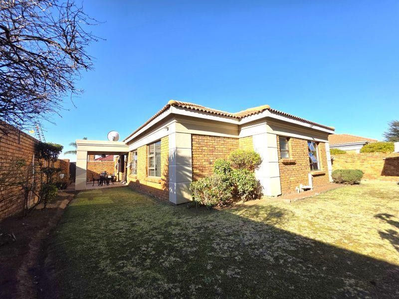 Rear view of a face brick house featuring a covered patio area and a private garden with boundary walls.