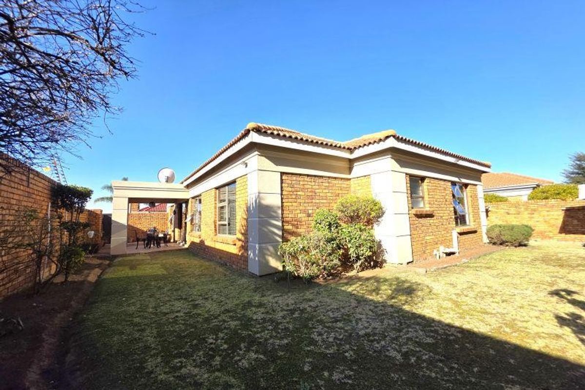 Rear view of a face brick house featuring a covered patio area and a private garden with boundary walls.