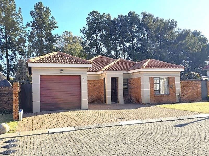 A well-maintained single-story house featuring a brick facade, tiled roof, paved driveway, and an integrated single garage.