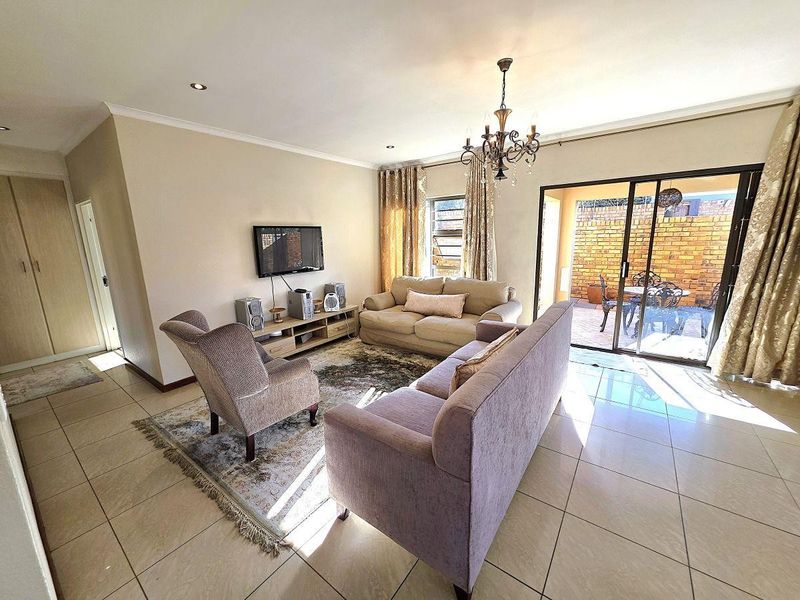 Spacious living room featuring tiled flooring, recessed lighting, and large sliding glass doors providing direct access to the outdoor patio area.