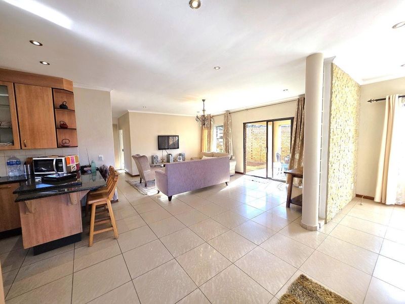 Spacious open-plan living area featuring a kitchen with granite countertops, tiled flooring, and sliding doors leading to an outdoor patio space.