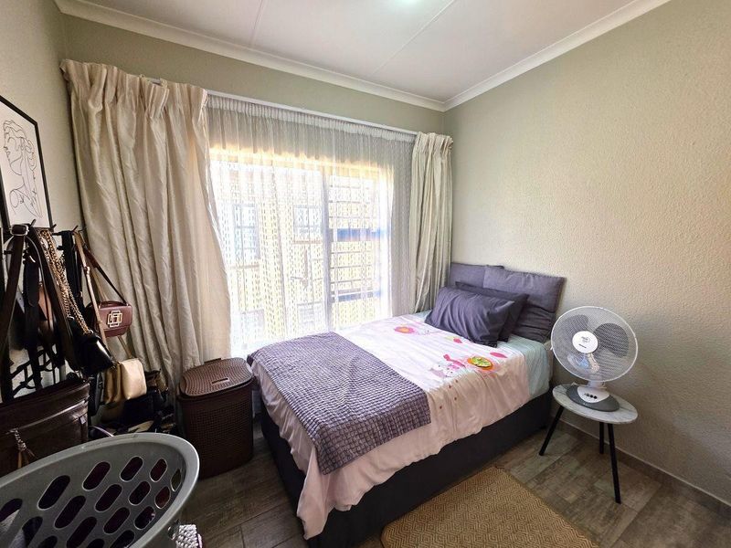 A compact bedroom featuring tiled flooring, neutral wall finishes, and a large window with natural light.