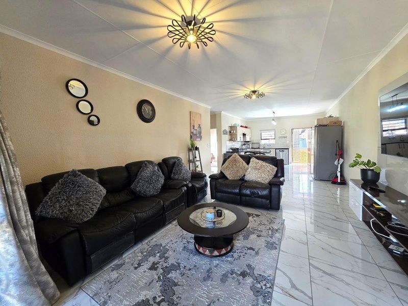 Spacious open-plan living area featuring modern tiled flooring, integrated kitchen cabinetry, and a seamless flow between the lounge and kitchen space.