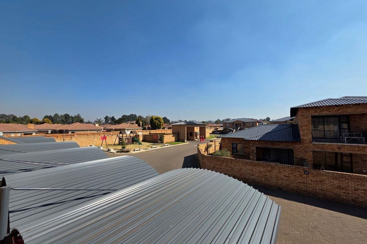 An elevated aerial view of the residential complex, showcasing the paved driveway, face brick structures, and metal roofing of the apartment units.
