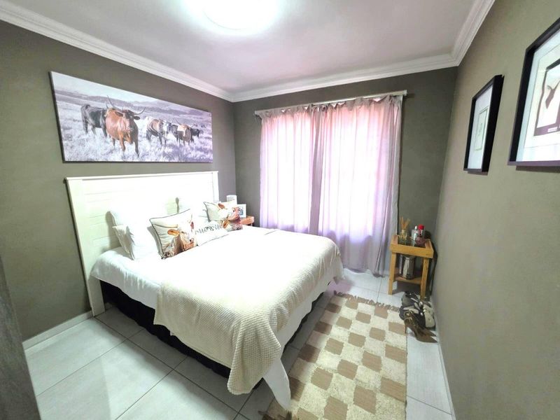 A well-maintained bedroom featuring neutral wall tones, tiled flooring, and crown molding, providing a comfortable and functional living space.