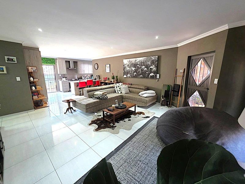 Spacious open-plan living area featuring polished tiled floors, recessed lighting, and a modern kitchen with a central island and built-in cabinetry.