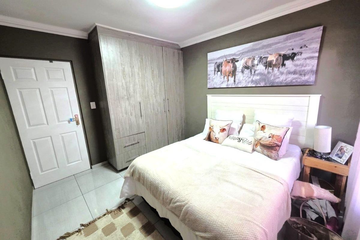 A well-maintained bedroom featuring neutral tiled flooring, built-in wooden cupboards, and decorative ceiling cornicing.