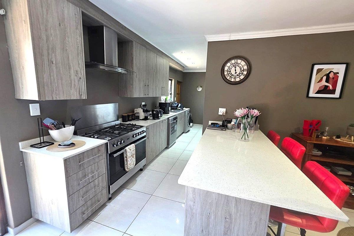 Modern kitchen featuring wood-grain cabinetry, stone countertops, a central island, and a gas stove with stainless steel extractor fan.