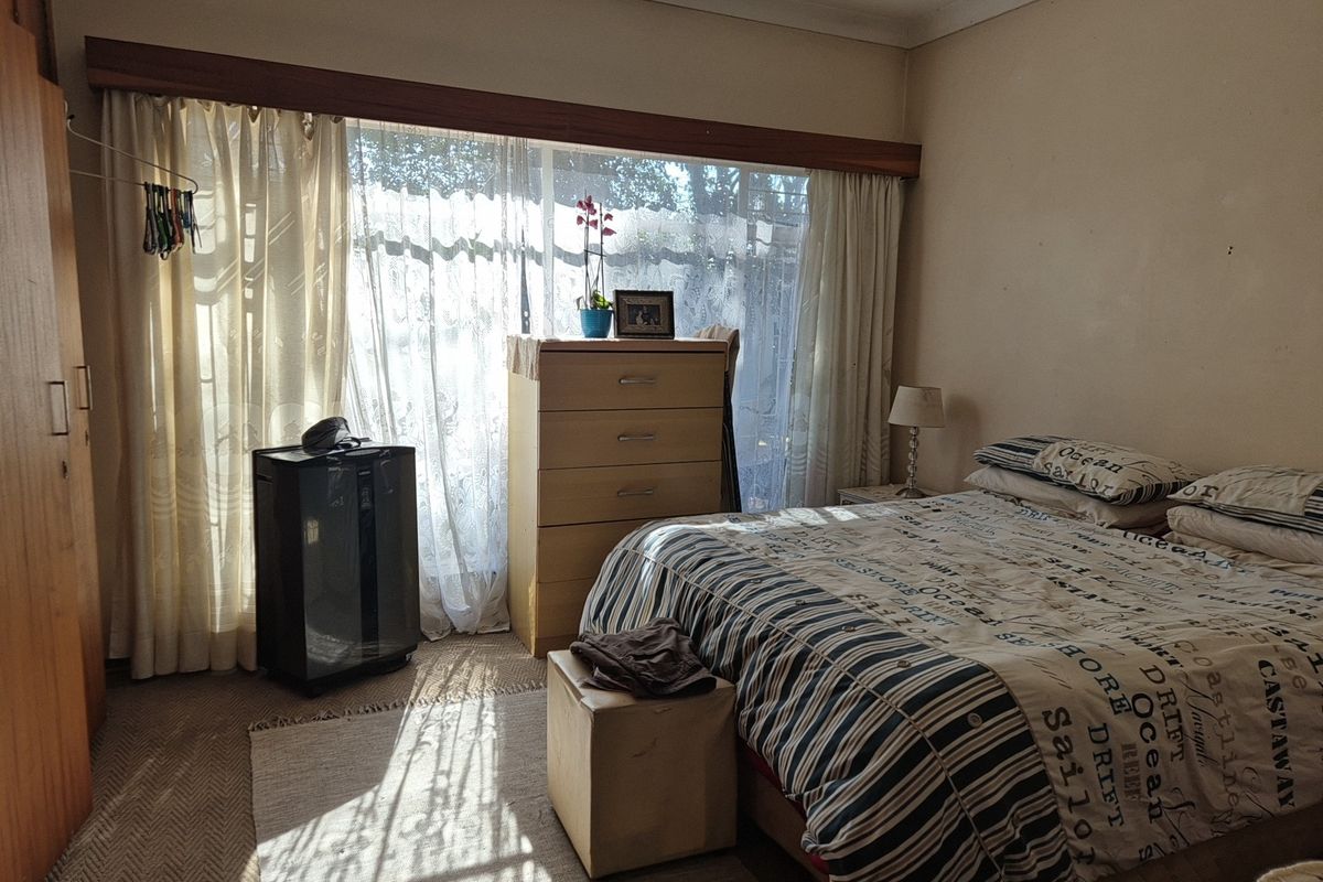 A bedroom featuring carpet flooring and a built-in wardrobe, offering a functional space with natural light from the large window.