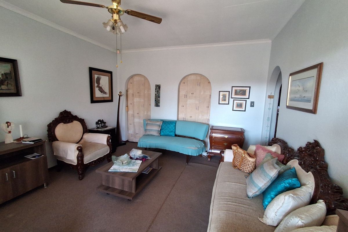 A living room featuring arched doorways and a ceiling fan, offering a traditional layout with neutral wall finishes.
