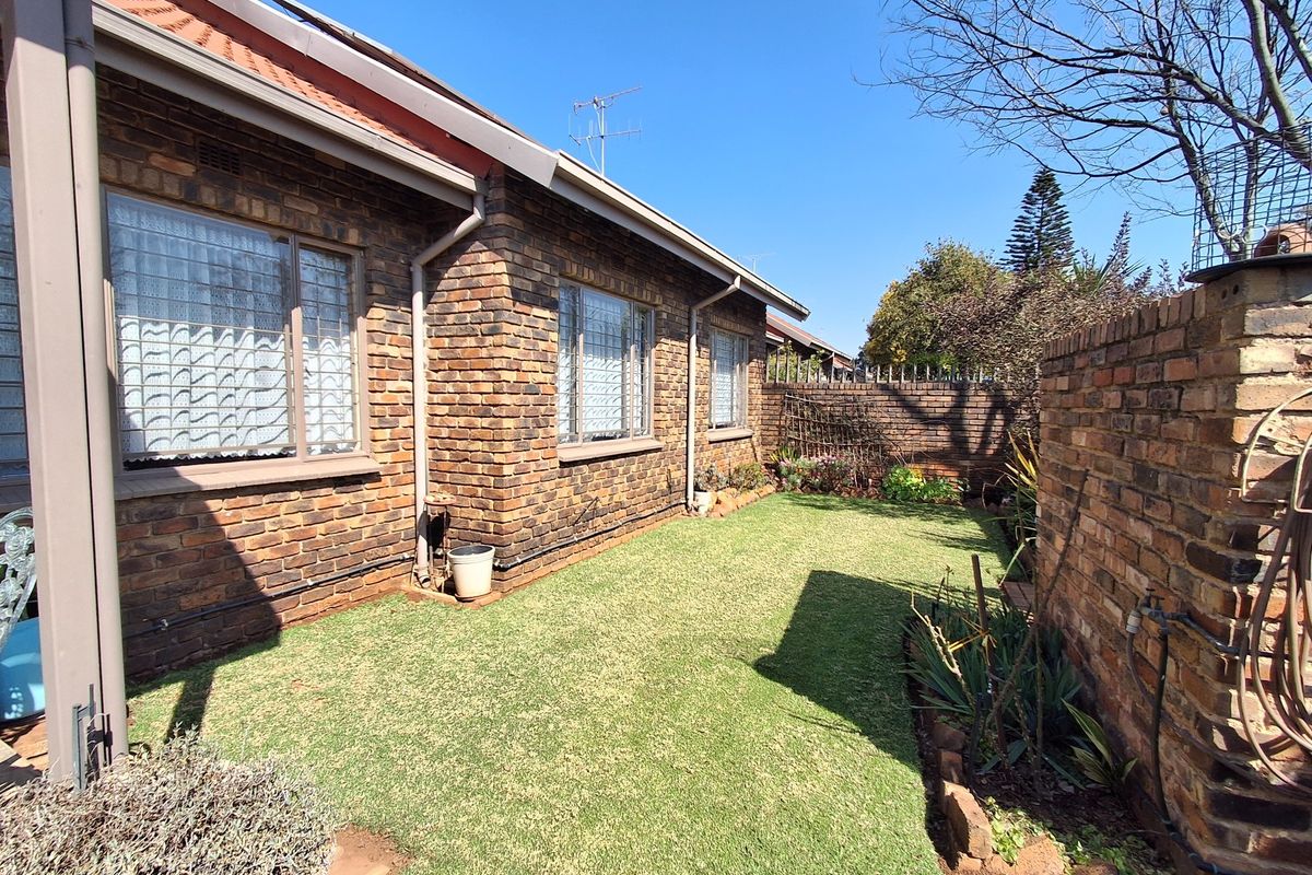 A private rear garden featuring a well-maintained lawn, face brick exterior walls, and secure boundary walling.