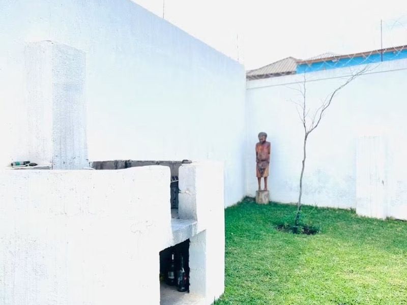 Rear garden area featuring a built-in masonry braai, enclosed by high perimeter walls with security razor wire.