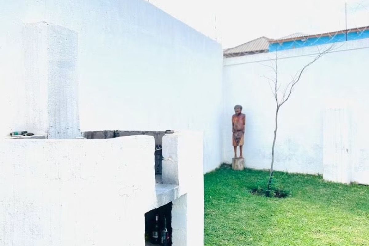 Rear garden area featuring a built-in masonry braai, enclosed by high perimeter walls with security razor wire.
