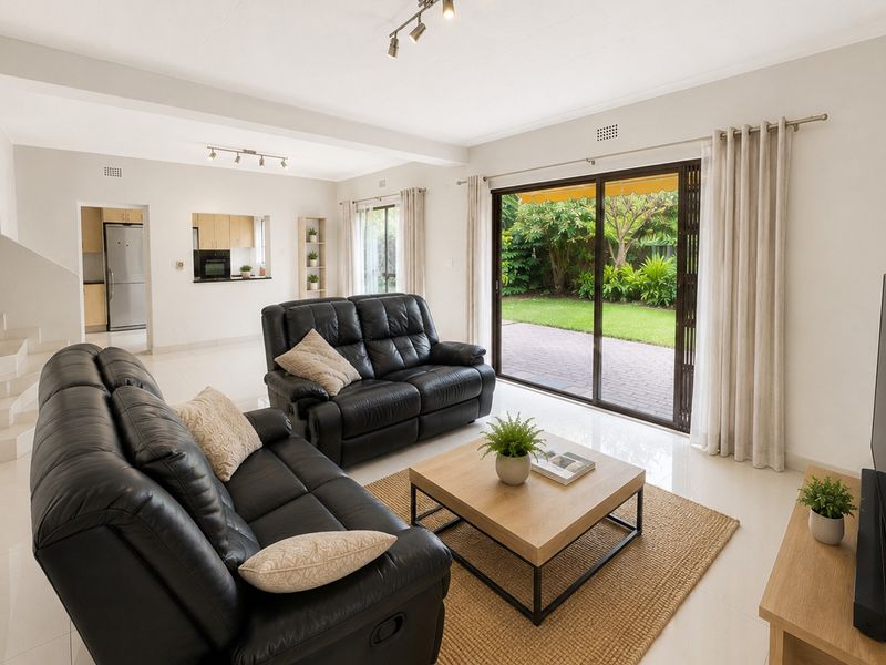 Spacious open-plan living area featuring tiled floors, modern track lighting, and large sliding glass doors providing seamless access to the rear garden.