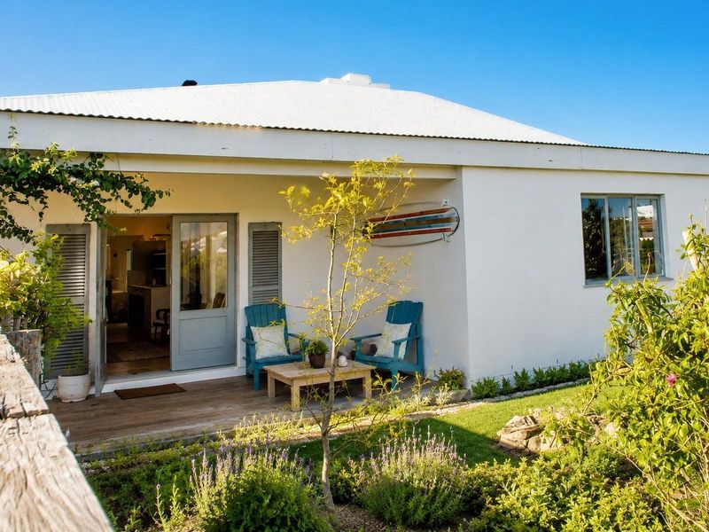Rear view of the property featuring a timber deck, white rendered walls, corrugated metal roof, and access through classic french doors.