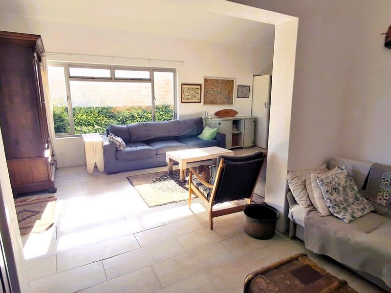 A spacious living area featuring light-toned tiled flooring and a large window that provides ample natural light.
