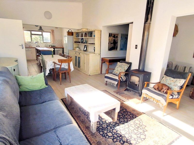 Open-plan living and dining area featuring a freestanding fireplace and tiled flooring, flowing into a functional kitchen space.
