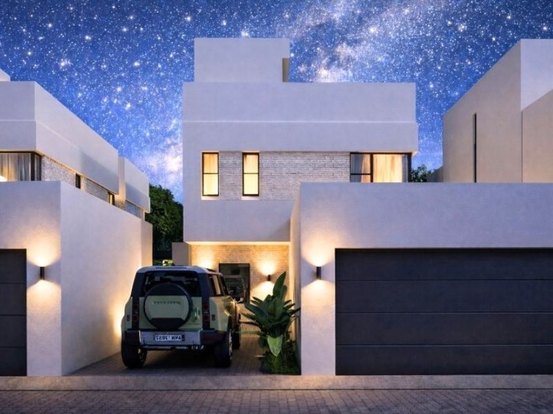 Modern townhouse front elevation featuring clean architectural lines, stone cladding accents, integrated garage, and warm exterior wall lighting.