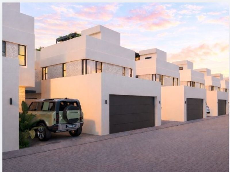 A row of modern townhouses featuring clean architectural lines, integrated garage doors, and paved driveway access in a contemporary residential estate.