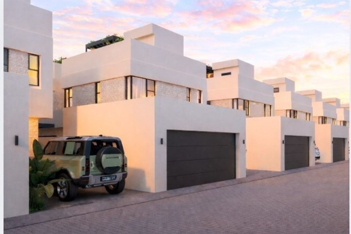 A row of modern townhouses featuring clean architectural lines, integrated garage doors, and paved driveway access in a contemporary residential estate.