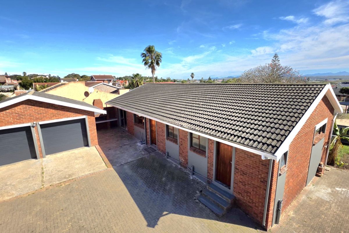 Aerial view of a brick-built residential property featuring a double garage, tiled roof, and paved driveway area.