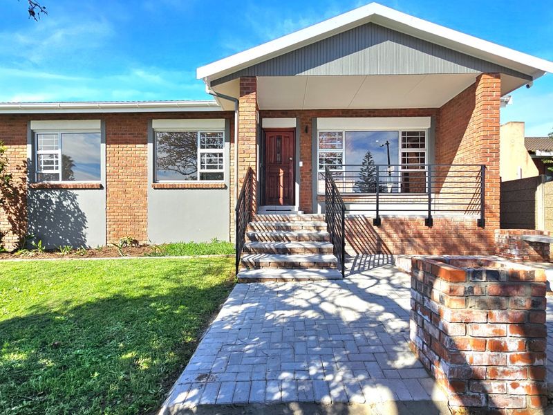 A well-maintained brick front facade featuring a covered porch, paved entrance walkway, and neat lawn area.