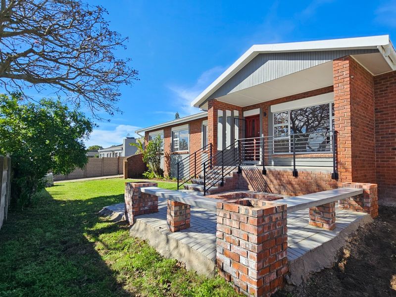 A well-maintained rear exterior featuring a brick patio with built-in seating, metal railings, and a classic brick facade under a gabled roof.