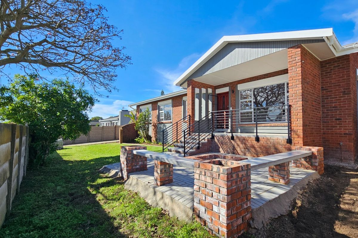 A well-maintained rear exterior featuring a brick patio with built-in seating, metal railings, and a classic brick facade under a gabled roof.