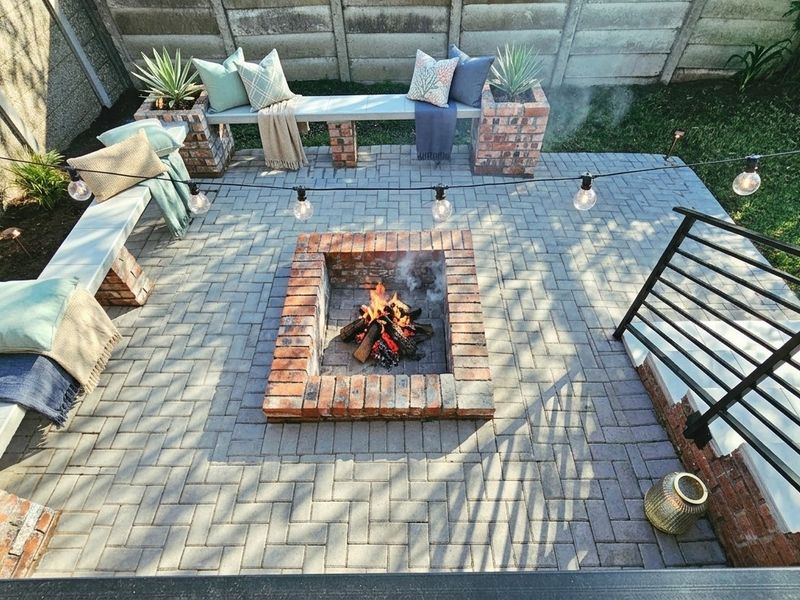 An inviting outdoor patio area featuring a central brick fire pit and built-in brick bench seating, perfect for entertaining.