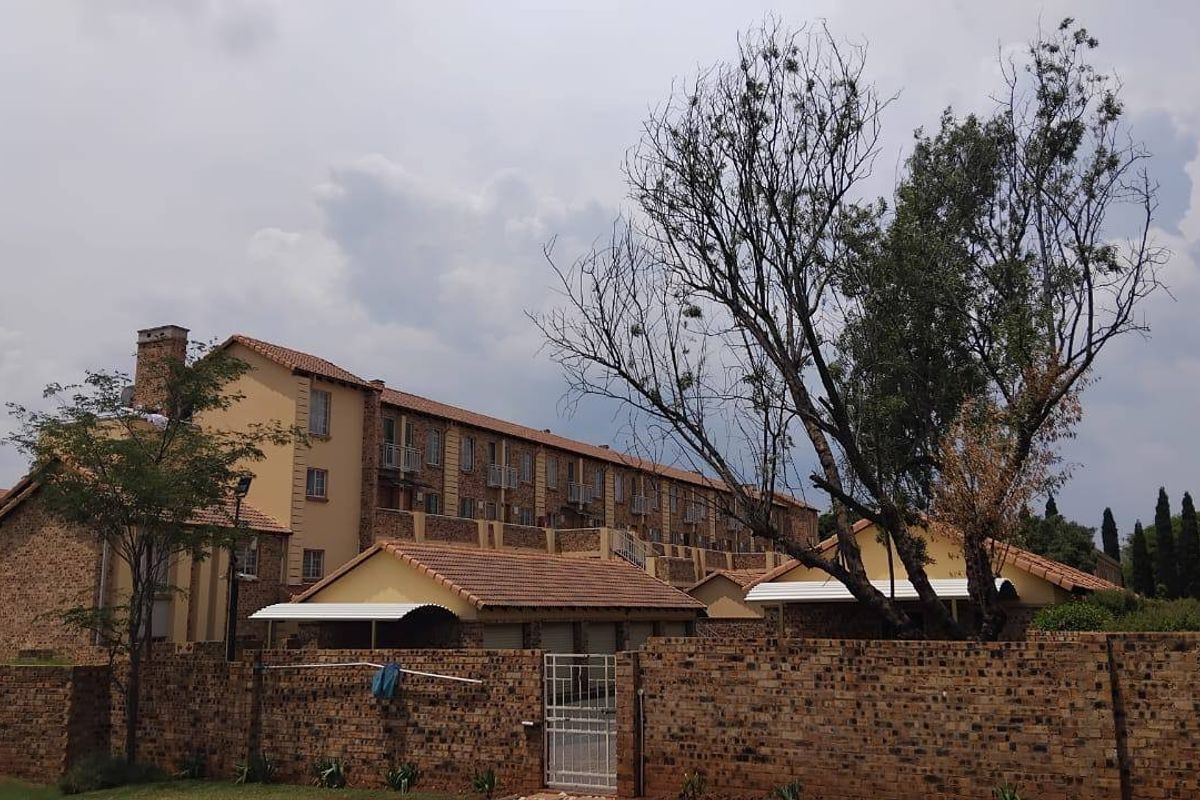 Exterior view of a multi-story apartment complex featuring face brick construction, tiled roofing, and private balconies.