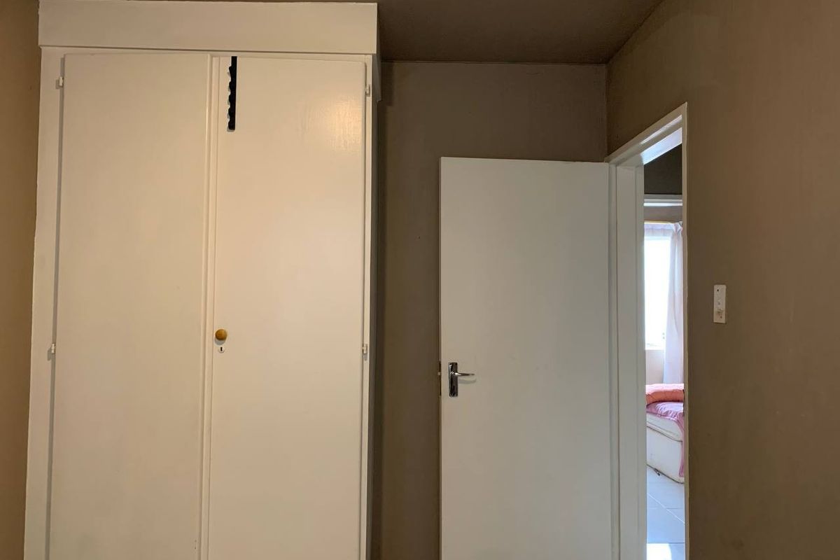 A bedroom featuring a built-in wardrobe and an open doorway leading to an adjacent room.