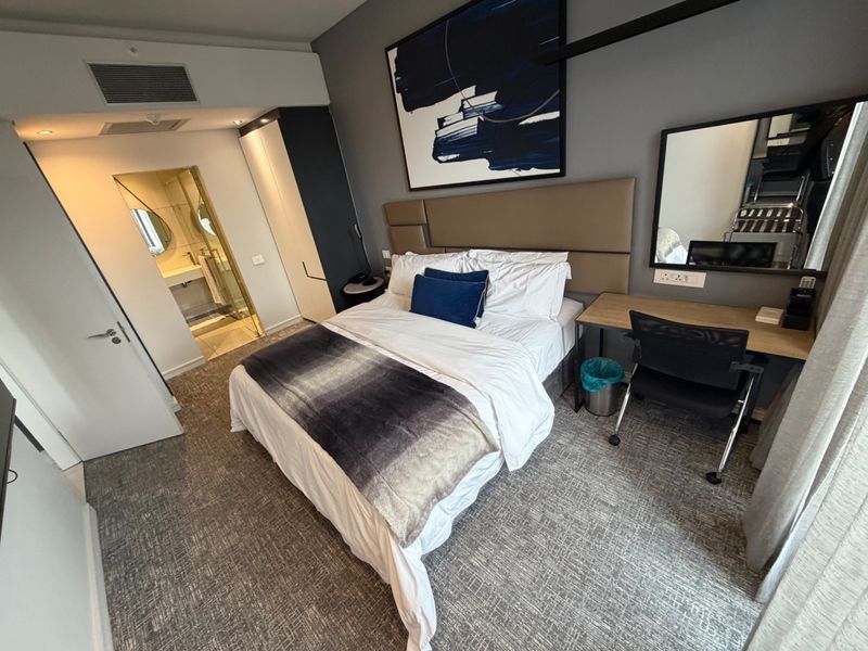 Modern bedroom featuring a built-in wardrobe, upholstered headboard, and an integrated en-suite bathroom with contemporary finishes.